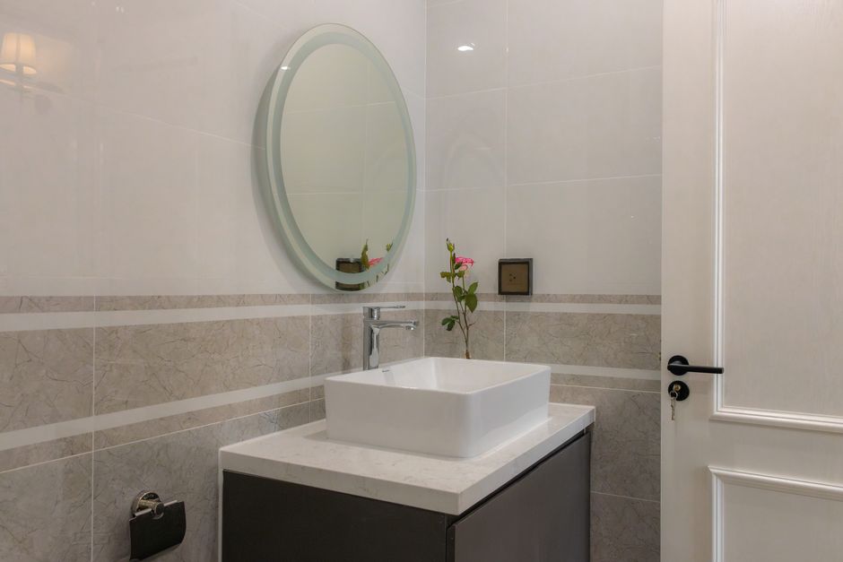Stylish modern bathroom with a round mirror and white sink.