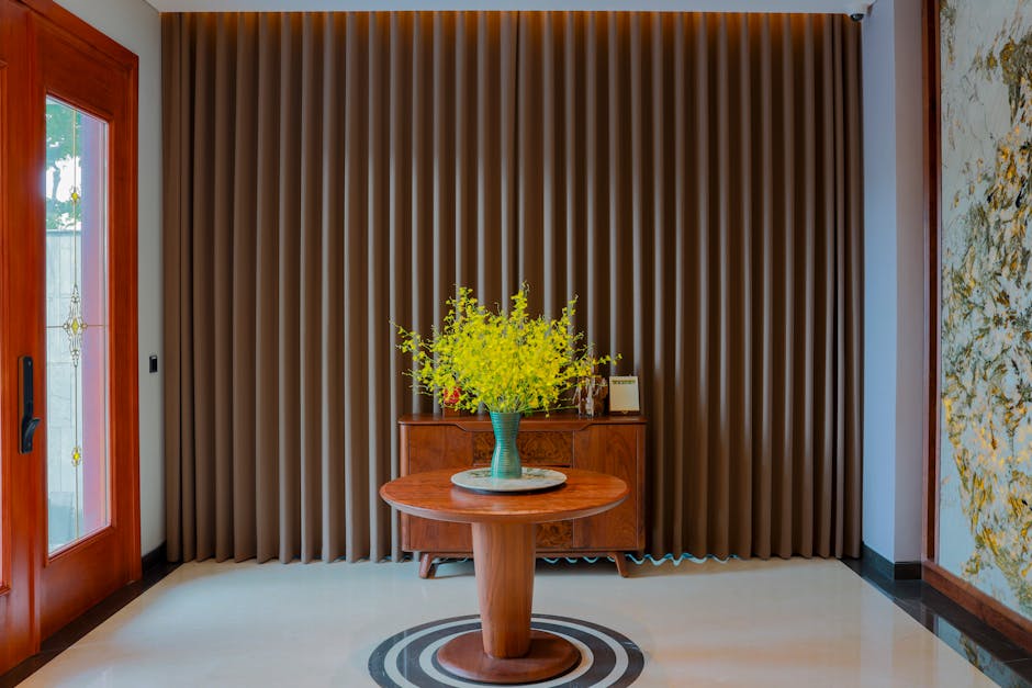Stylish interior featuring a wooden table, vase with yellow flowers, and elegant curtains.