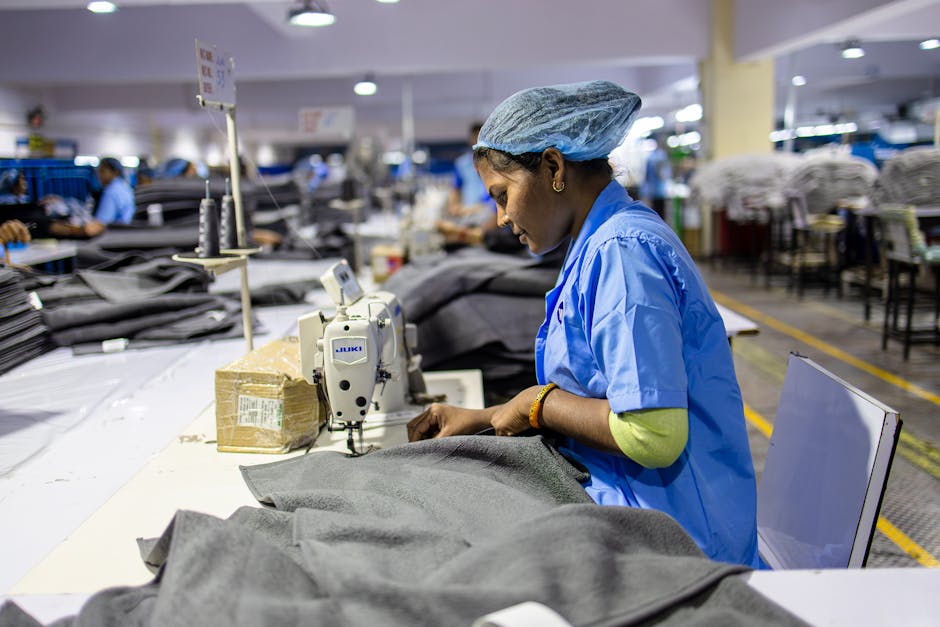 Female worker sewing in a busy textile factory, highlighting industrial skill.