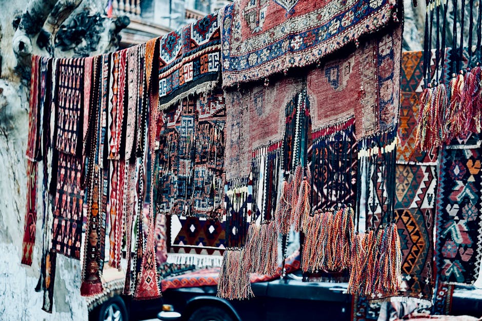 Colorful handmade rugs with intricate patterns displayed outdoors for sale.
