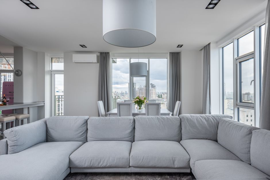 Comfortable large sofa decorating white contemporary living room with table and chairs in apartment