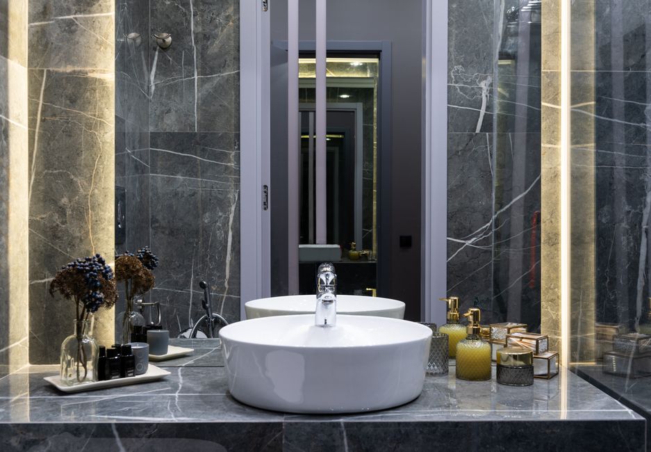 Contemporary bathroom with washstand between plant sprigs and hygiene products against mirror in house