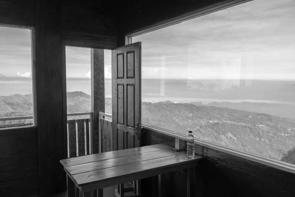 Serene mountain landscape through open cabin door, captured in black and white.