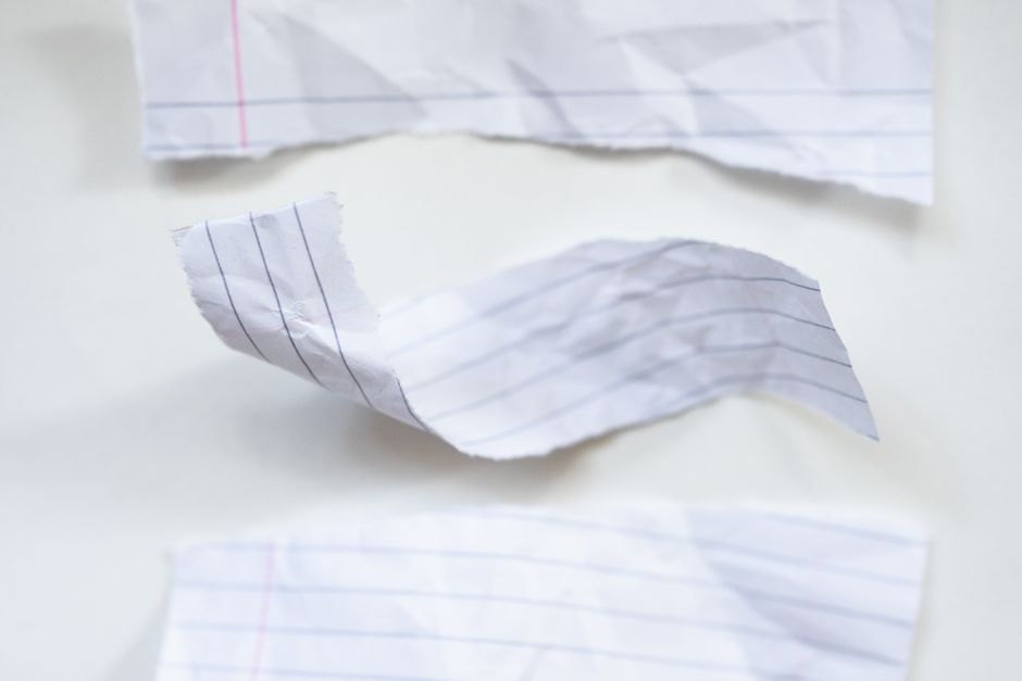 Close-up view of crumpled lined papers on a white surface. Ideal for background or texture use.