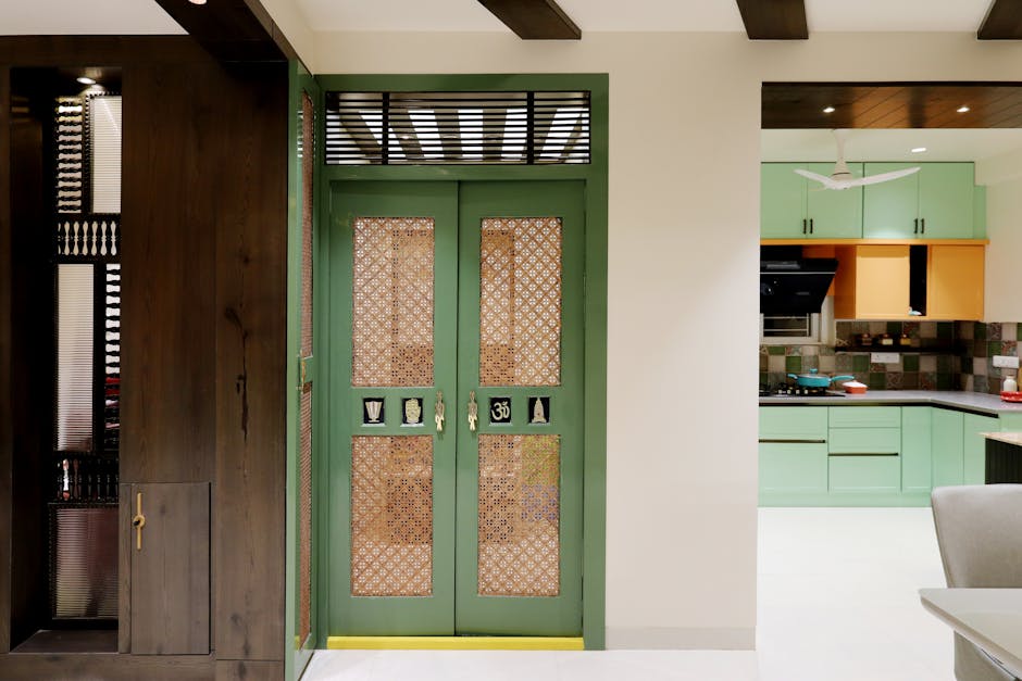 Interior view featuring a stylish Indian home entrance with intricate door designs leading to a modern kitchen.