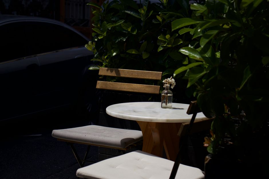 Charming garden patio featuring wooden chairs and table with flowers in a jar, ideal for relaxation.