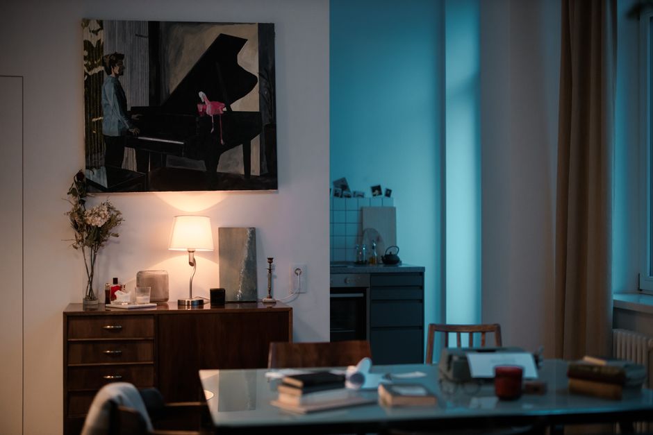 A cozy living area with eclectic art, warm lighting, and a glimpse into a modern kitchenette.