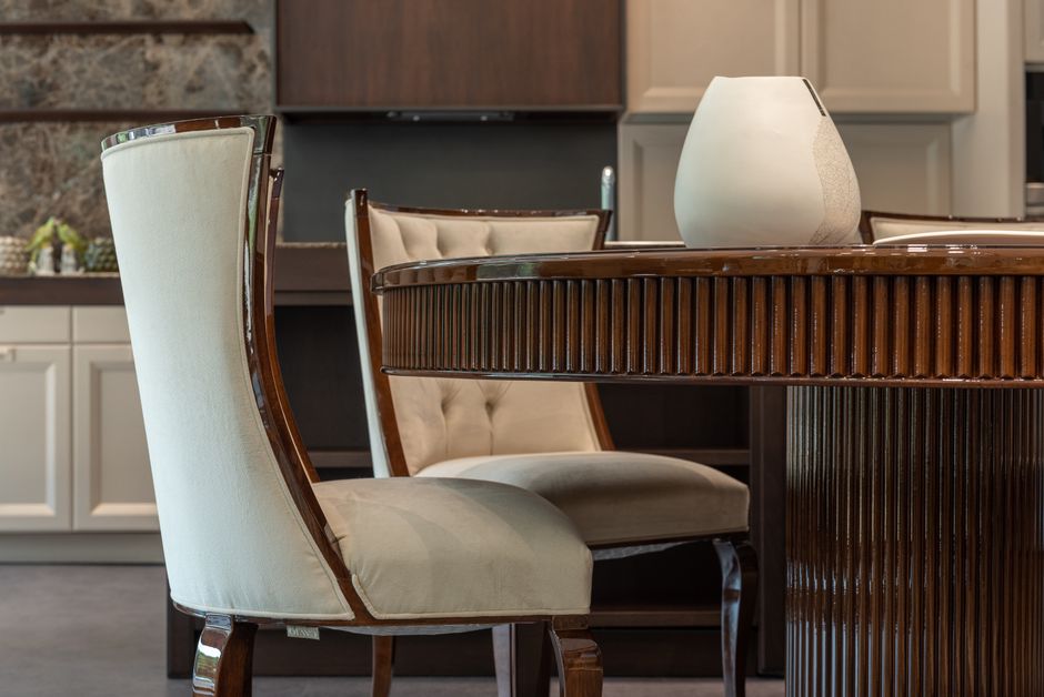 Comfortable soft chair and round wooden table placed in spacious kitchen in classic styled apartment in daytime