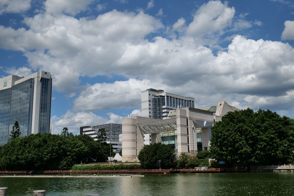 Contemporary buildings by a lake with blue skies and clouds.