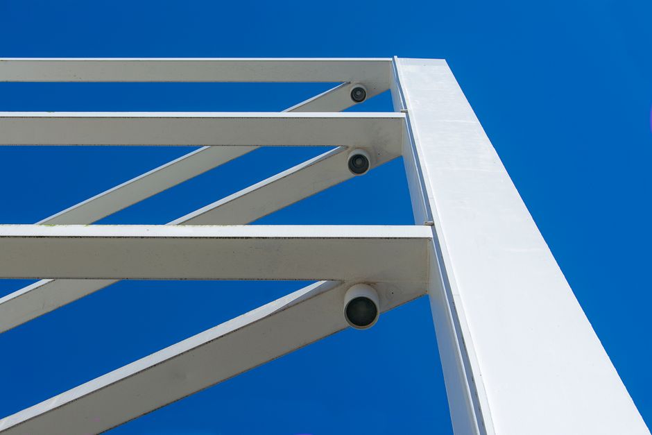 Low angle view of modern white beams against a bright blue sky, emphasizing urban architecture.