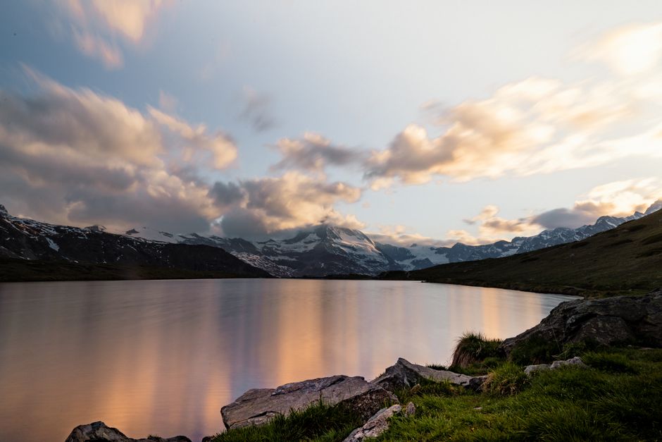 Serene view of Zermatt's lake and snow-capped mountains during sunset. Peaceful and picturesque landscape.