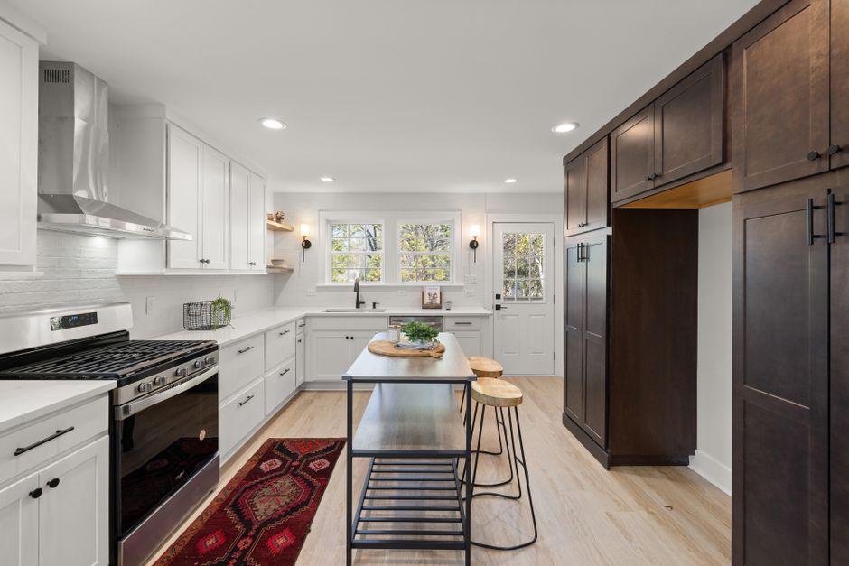 Spacious modern kitchen with a blend of white and dark wood cabinetry, featuring a central island.
