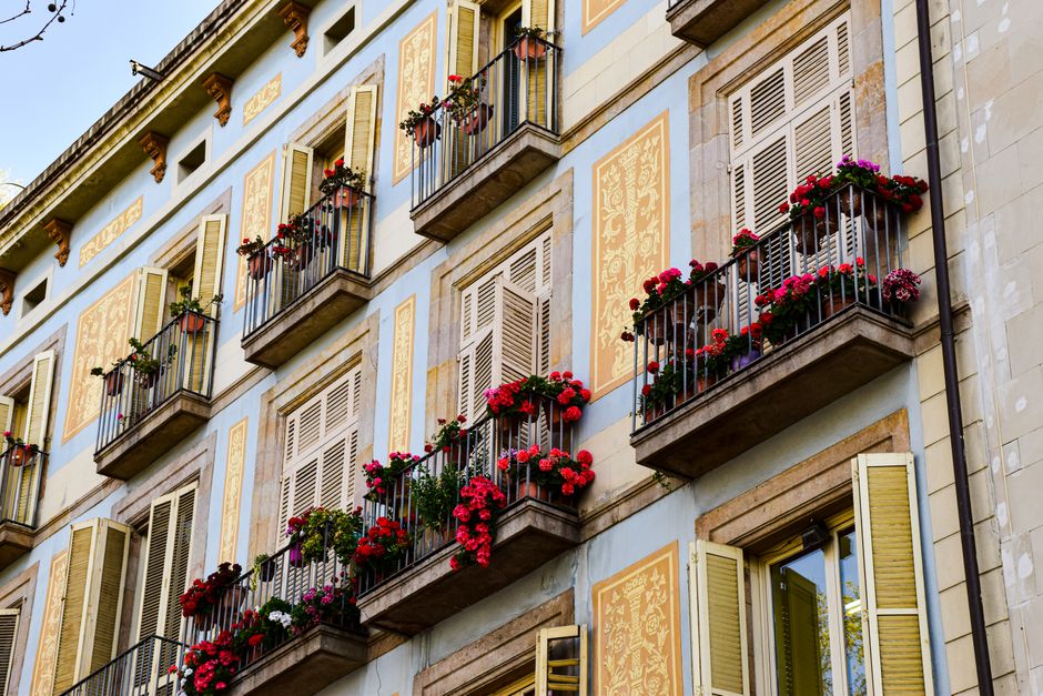 Colorful floral balconies on a traditional Barcelona apartment facade, capturing vibrant urban charm.